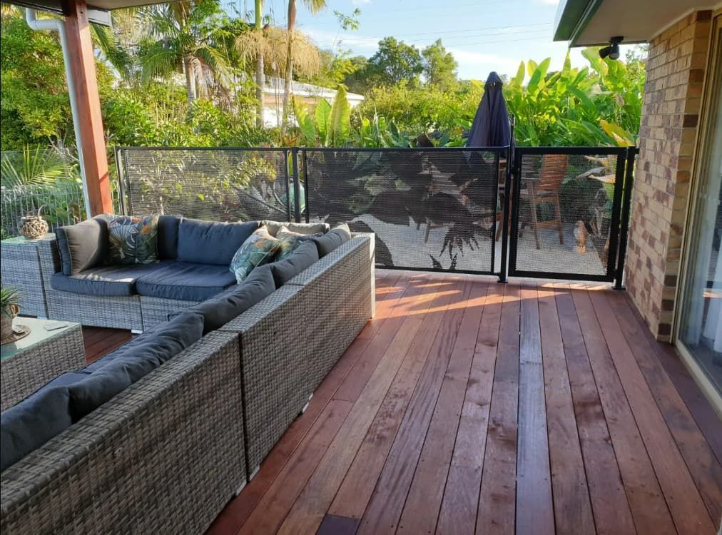 A Wooden Deck With A Couch And Umbrella On It — Coastal Blind Installations In Kensington, QLD