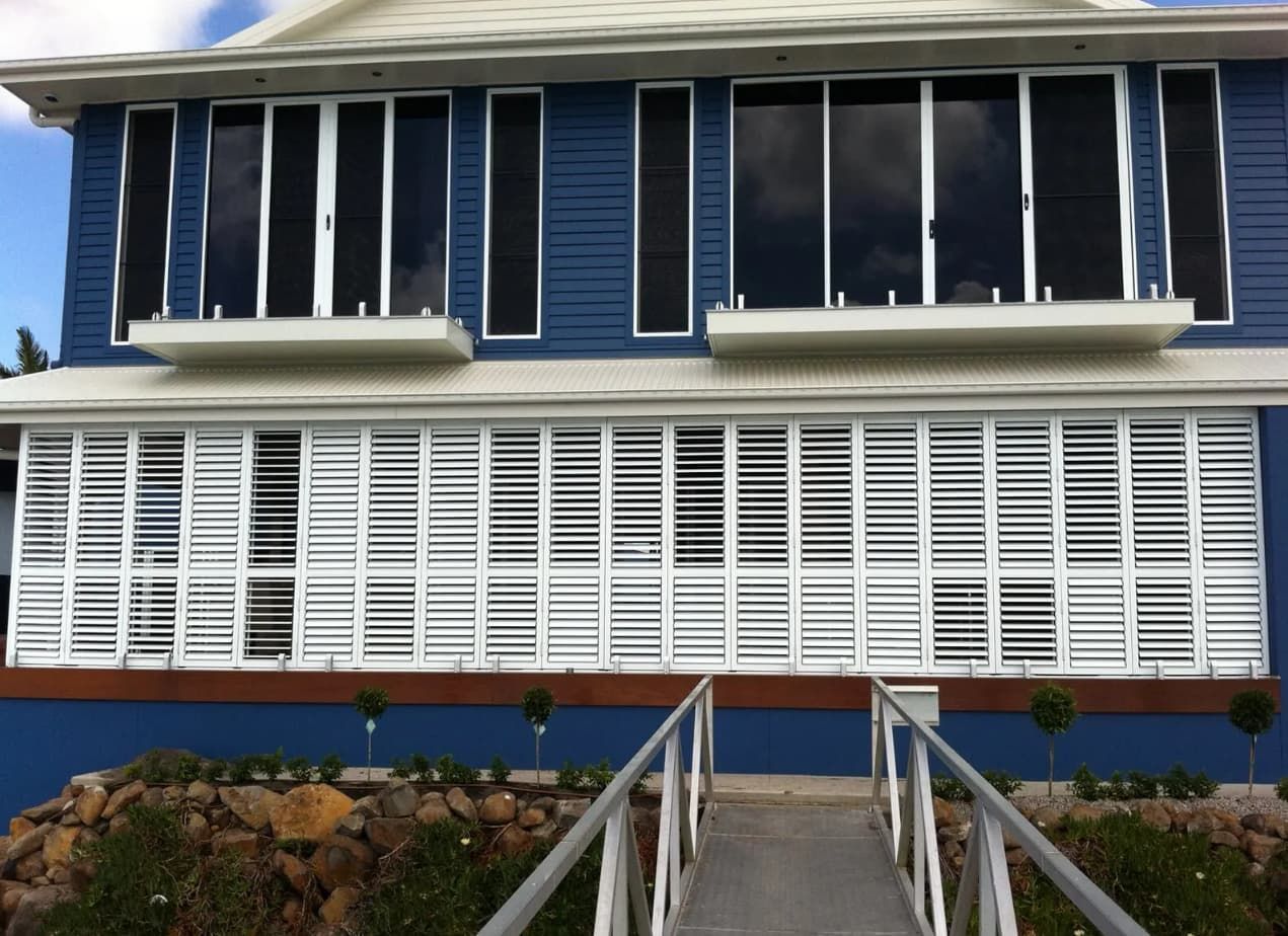 A Blue House With White Shutters And A Ramp Leading To It — Coastal Blind Installations In Kensington, QLD