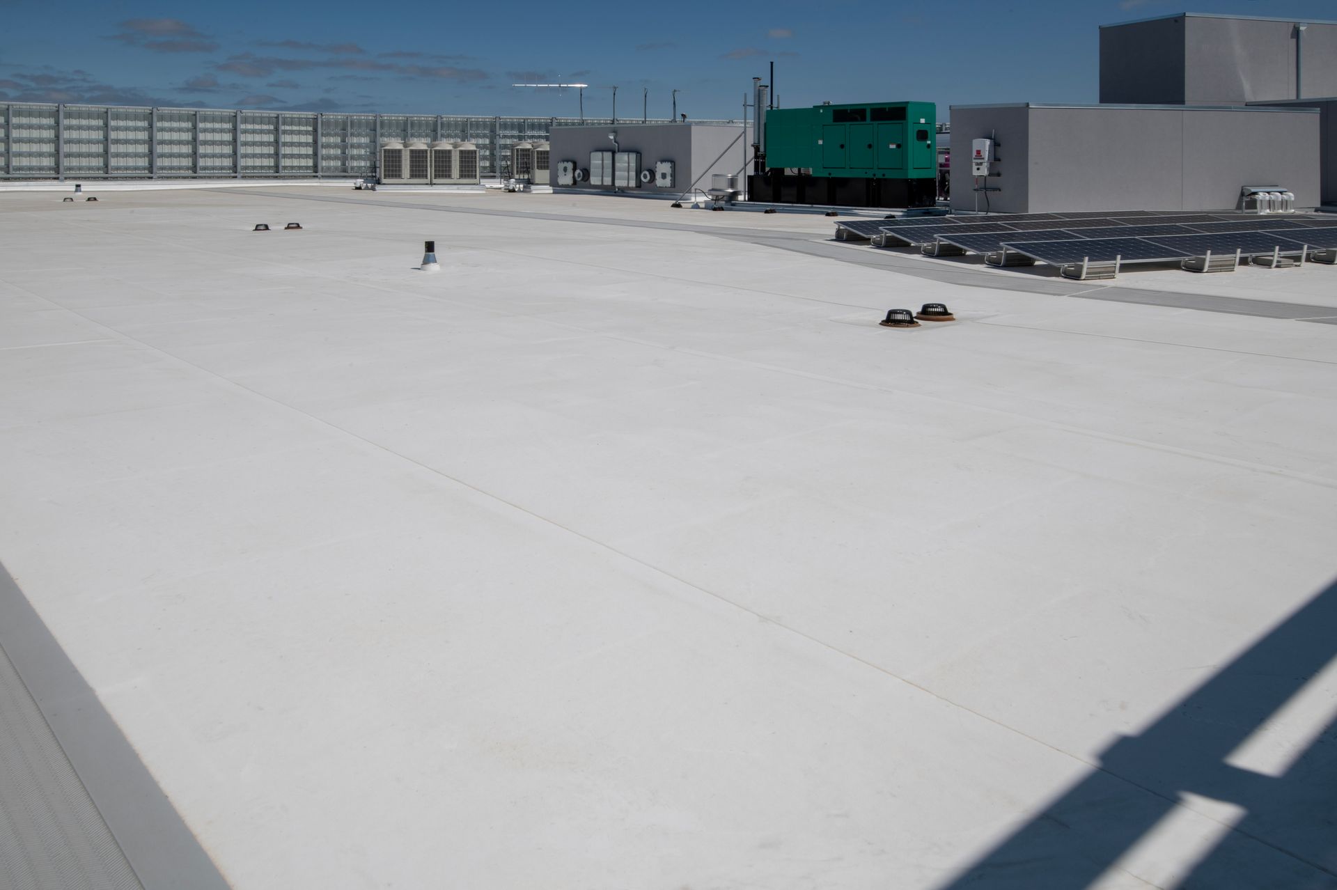 Aerial view of a commercial flat roofing featuring multiple solar panels for energy efficiency.