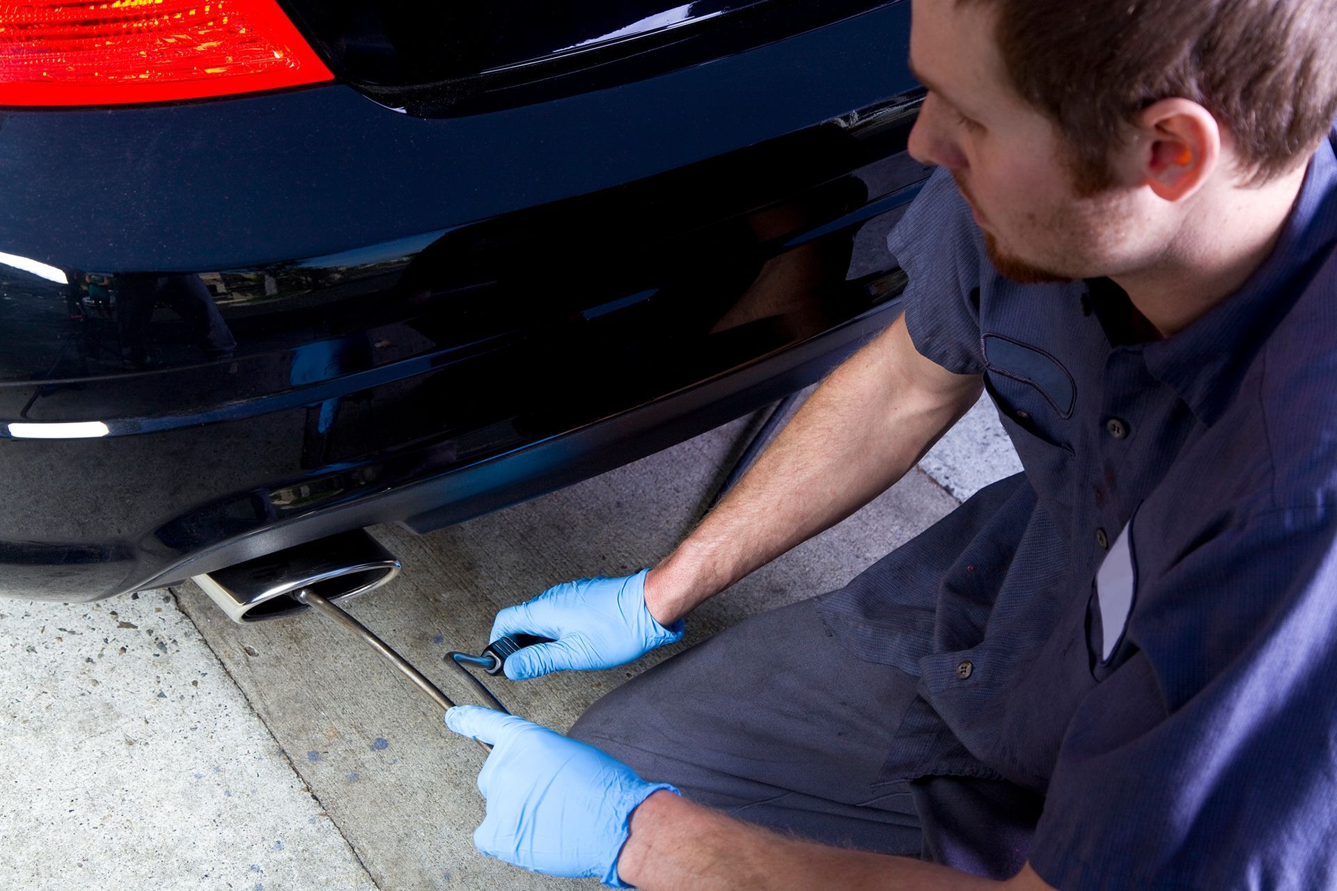 A man wearing blue gloves is working on a car