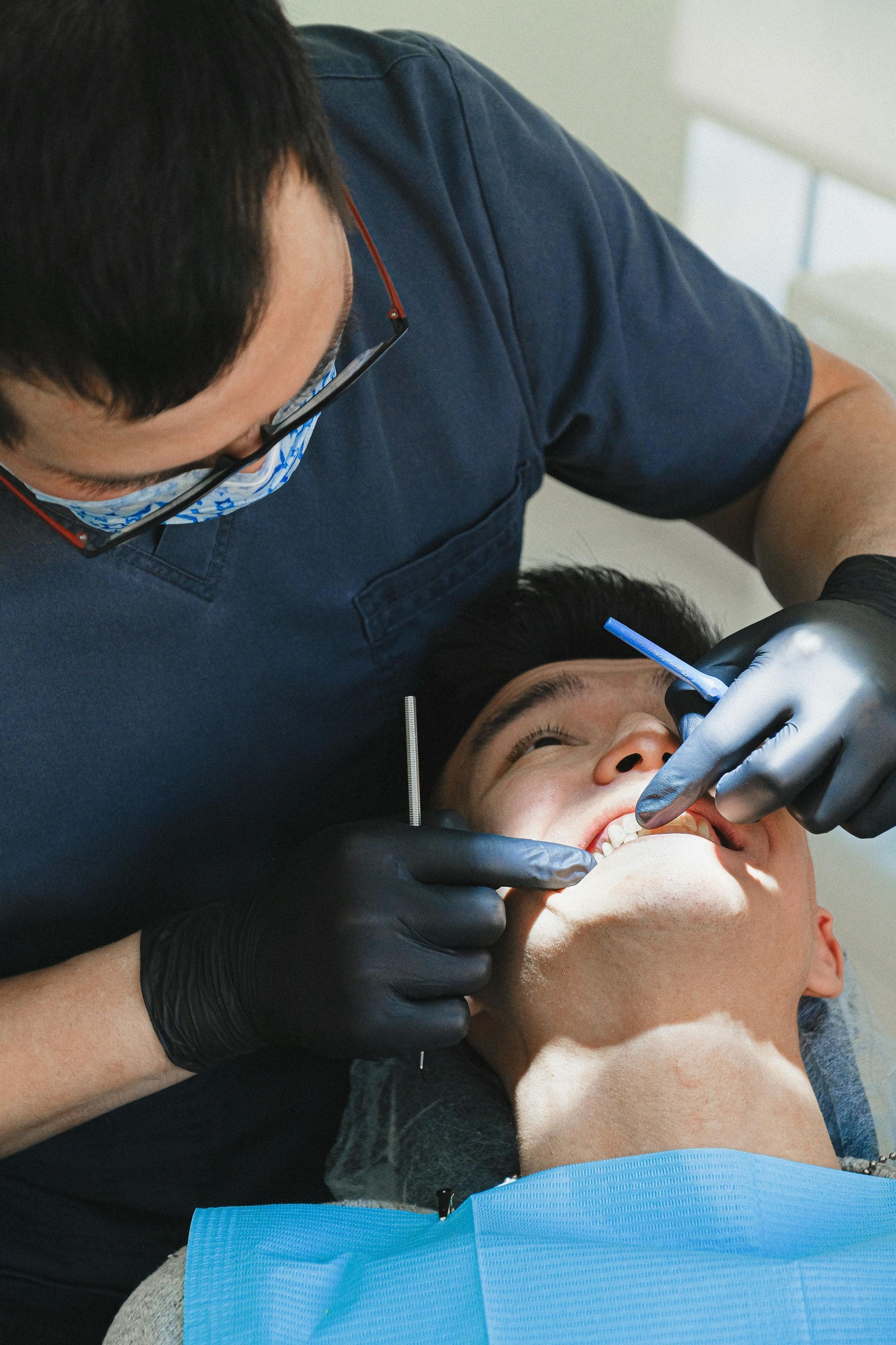 Dentist examining patient's teeth with tools in a dental office.