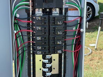 Electrical panel with black, red, and green wires connected to circuit breakers.