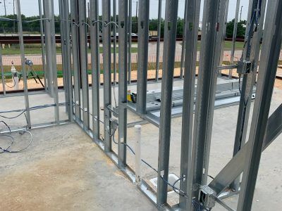 Metal studs frame a building's interior walls. Electrical wiring and a pipe are visible.