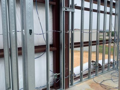 Metal framing of a wall, possibly under construction, with visible insulation and wiring.