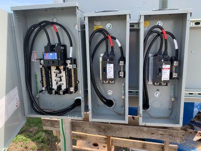 Electrical boxes with wiring and breakers outdoors.