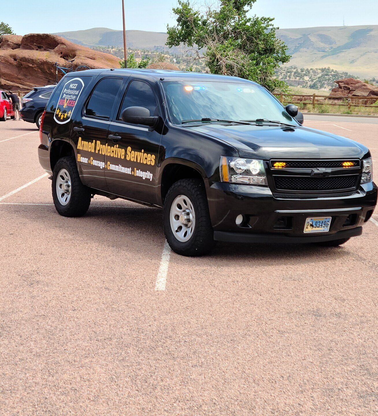 A black suv is parked in a parking lot that says roof protection services