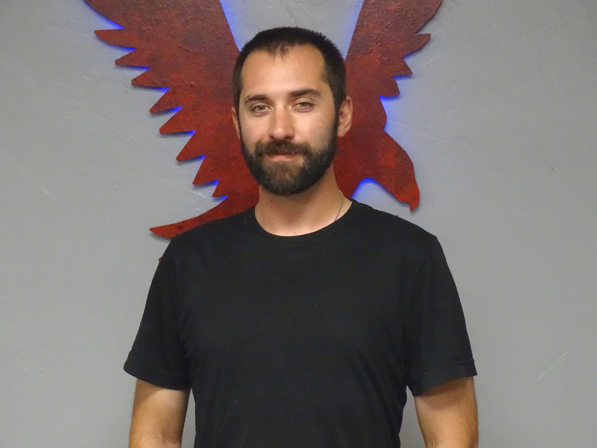 A man in a black shirt is standing in front of a red eagle