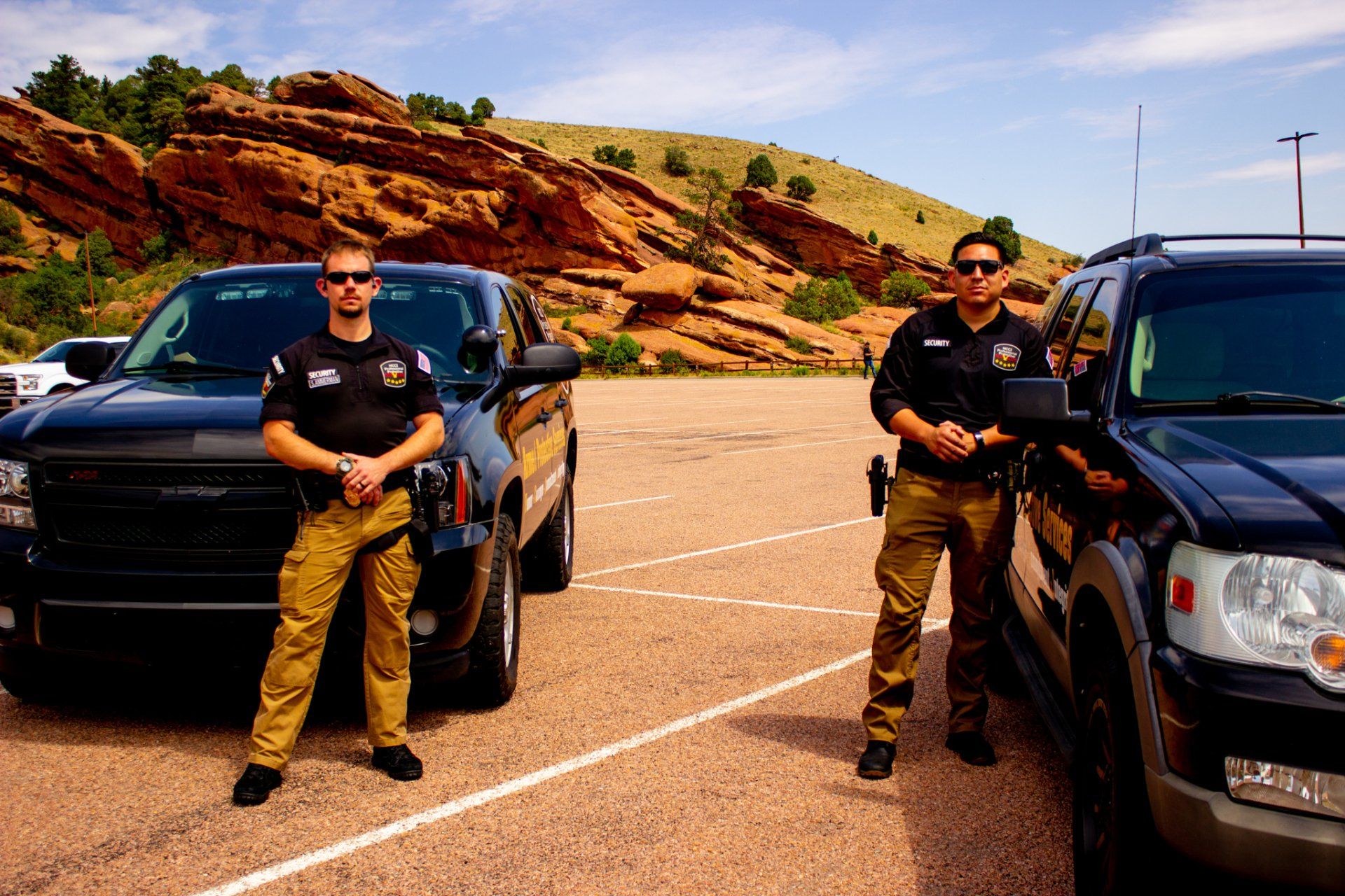 Two police officers standing next to a black suv in a parking lot
