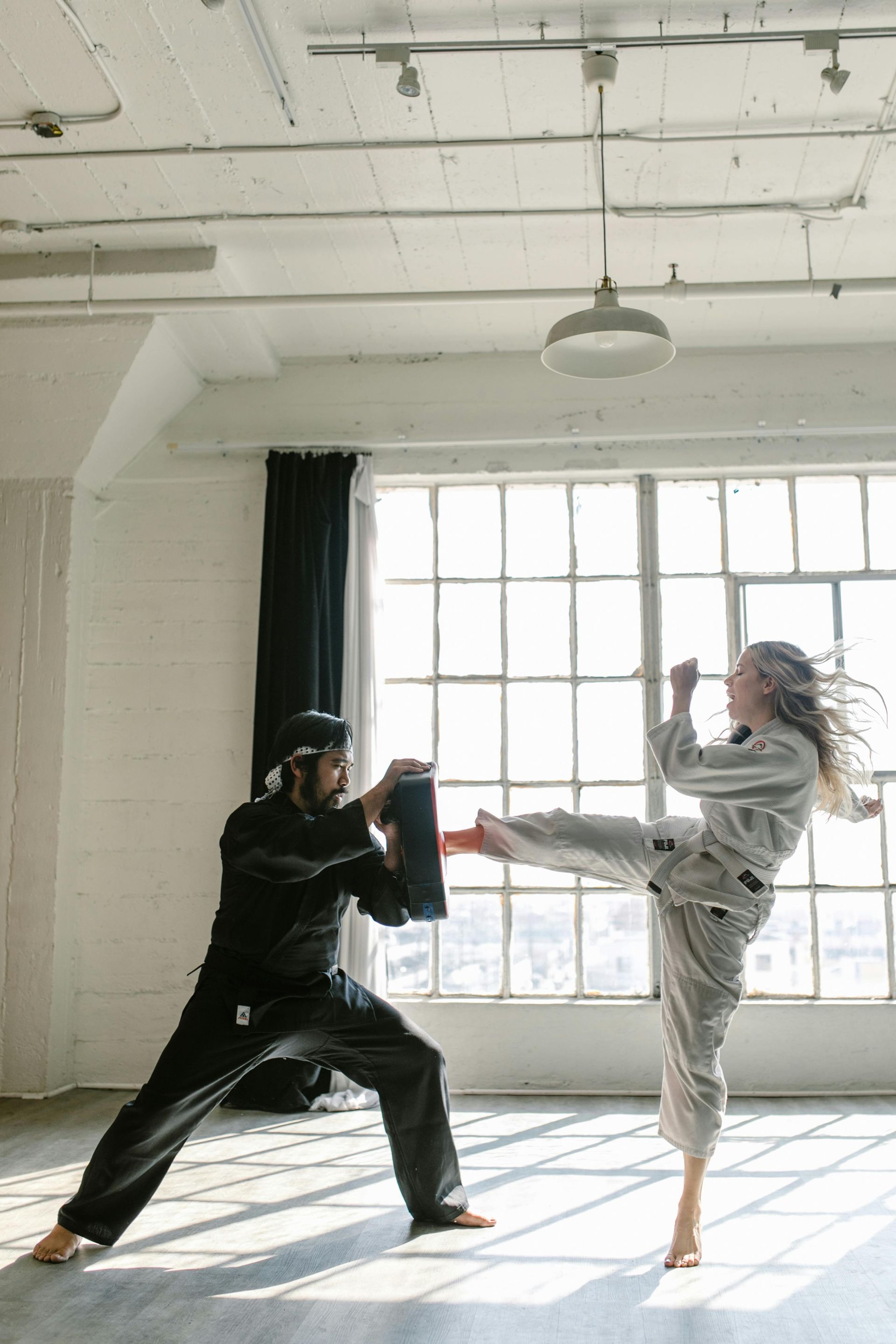 A man and a woman are practicing karate in a room.