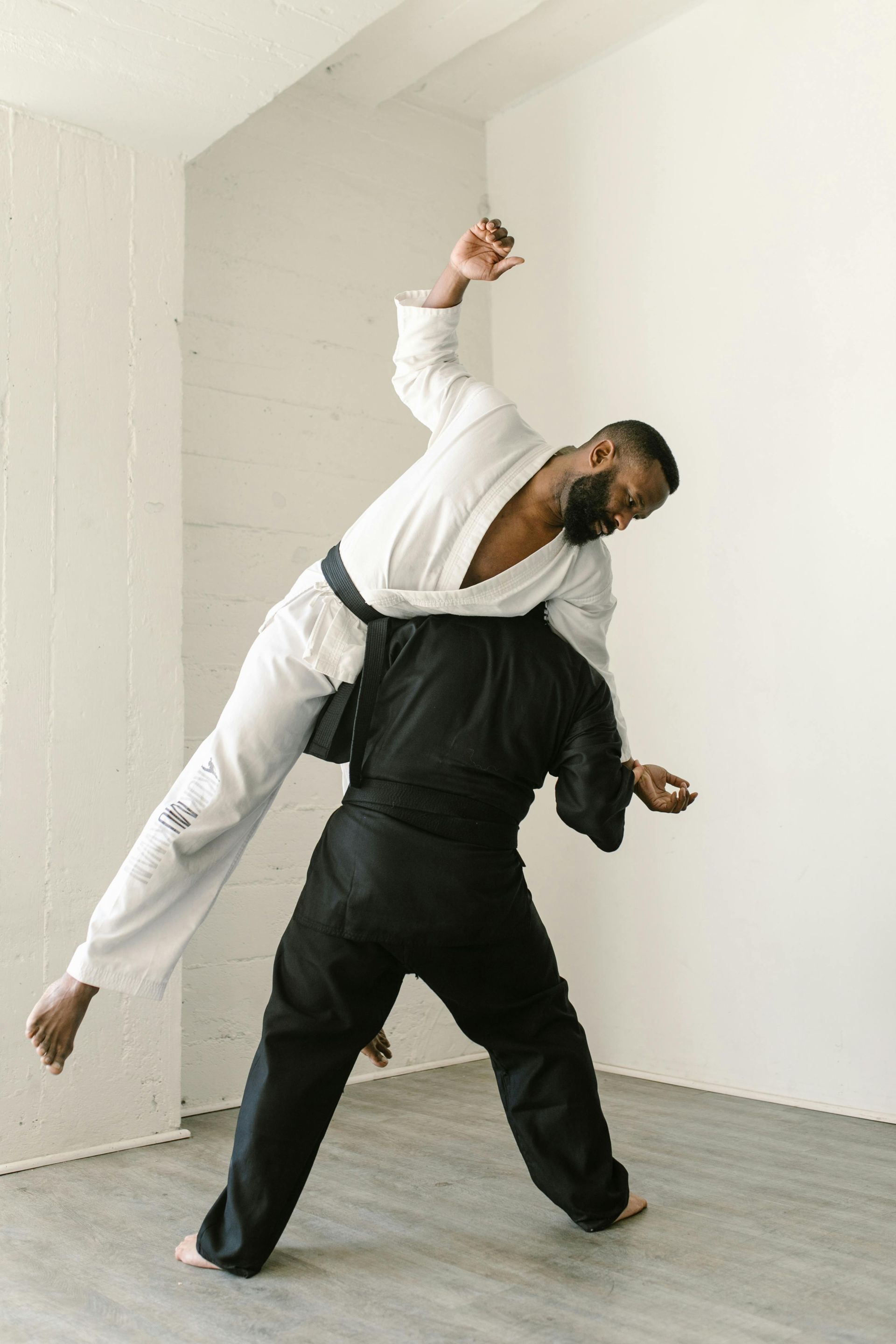 Two men are practicing martial arts in a room.