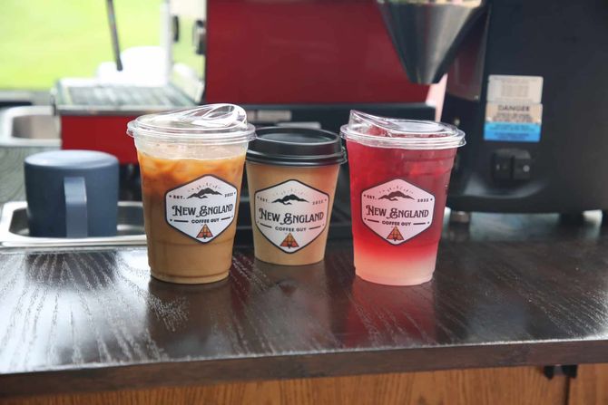 Three cups of coffee are sitting on a wooden counter.