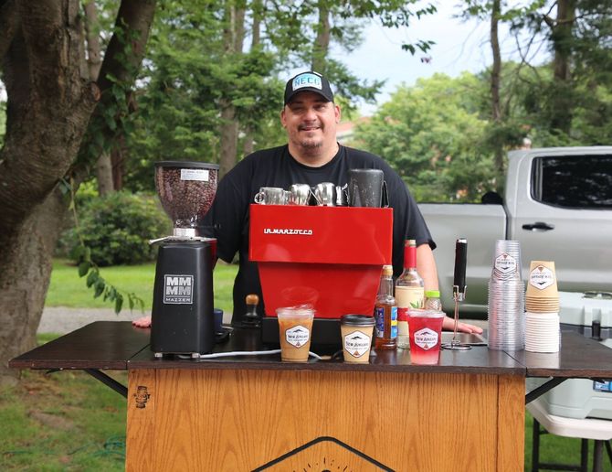 A man is standing in front of a red coffee machine.