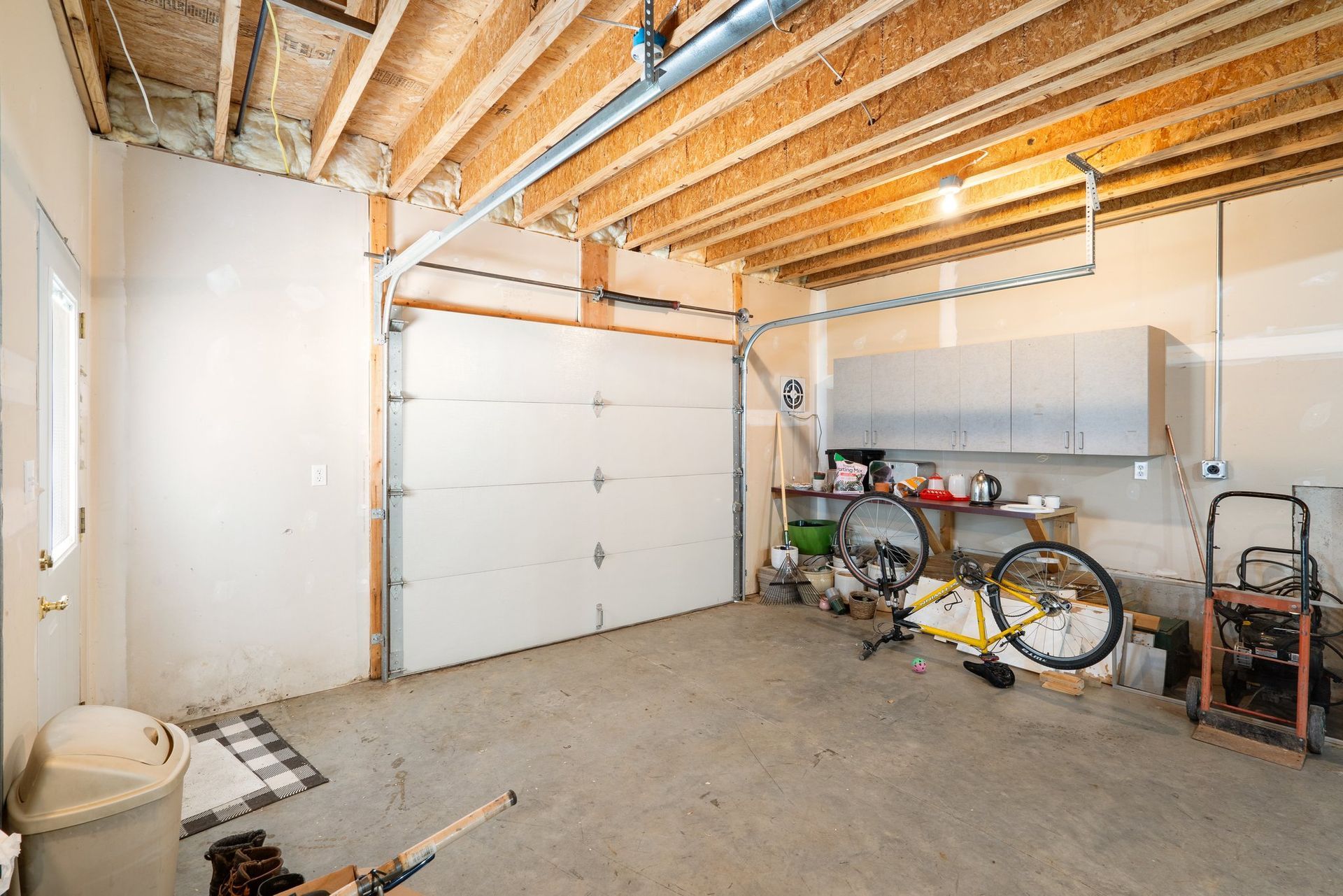 Garage interior with closed white garage door, bicycle, and storage cabinets.