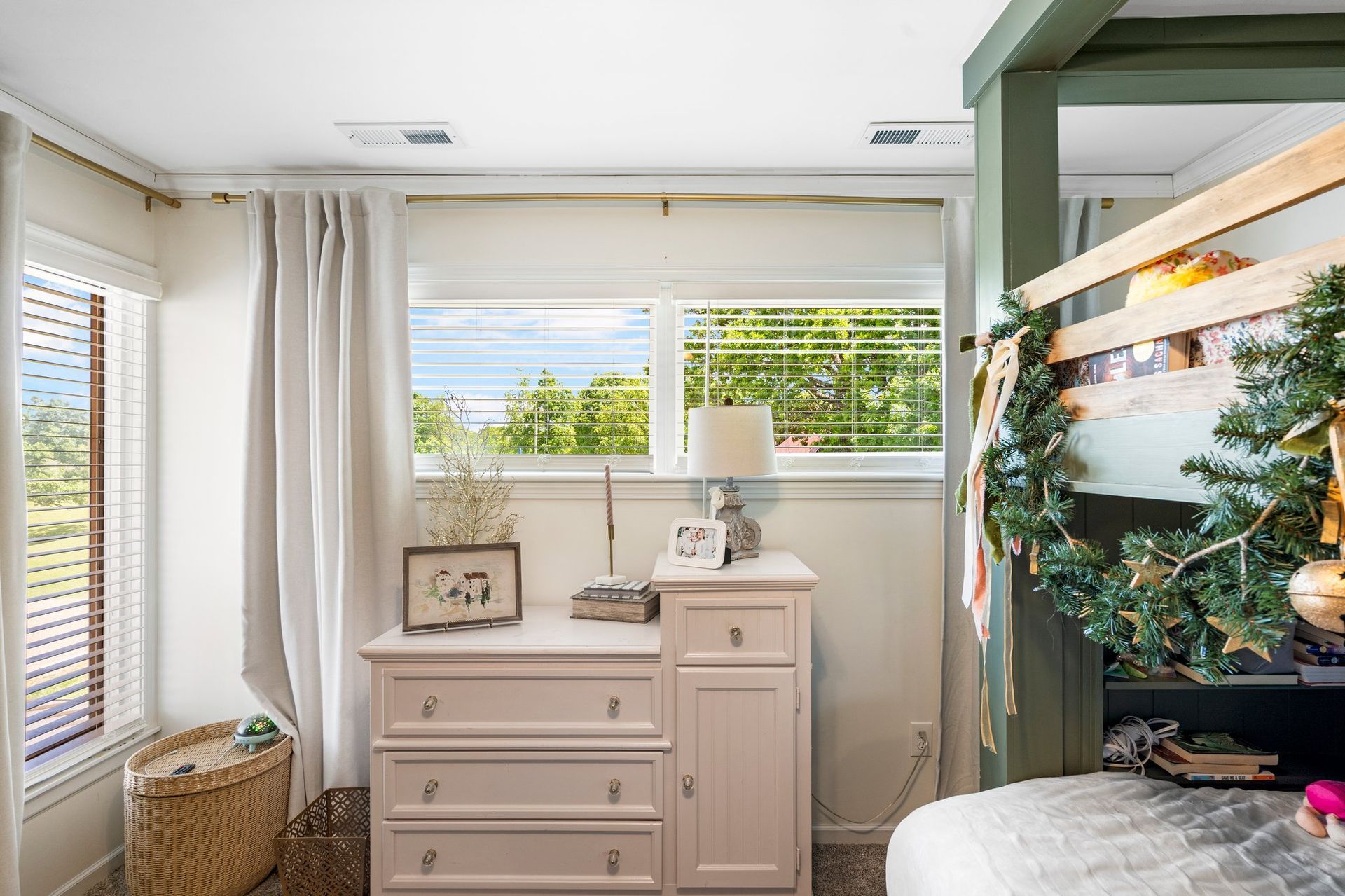 Bedroom with a dresser, window, and bed with a garland.