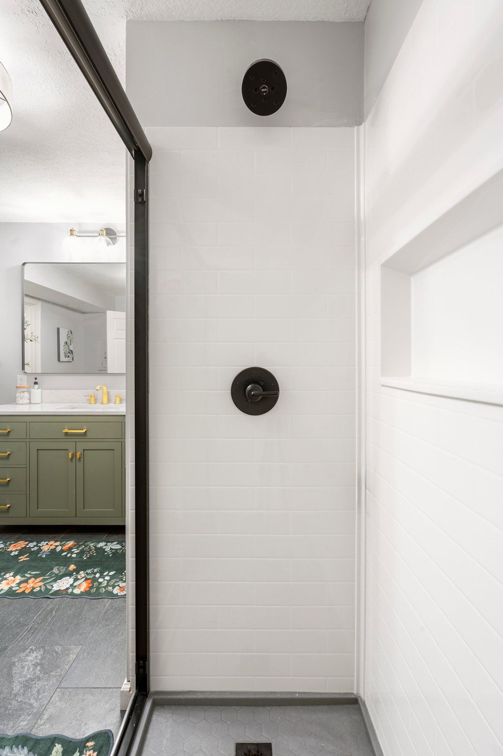 Bathroom interior with white walls, black shower fixtures, and a glass door.