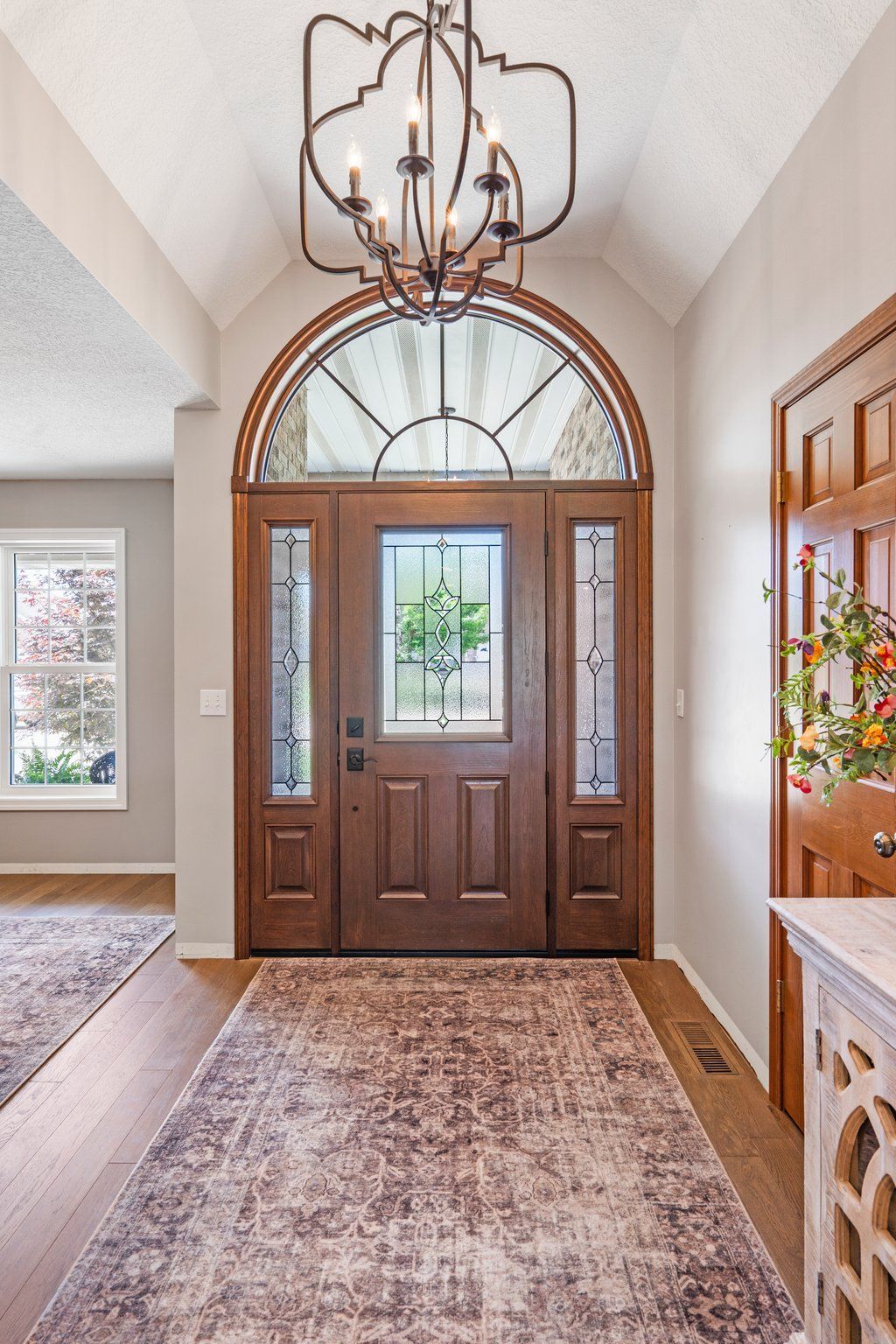 A wooden entryway door with an arched window at the top.