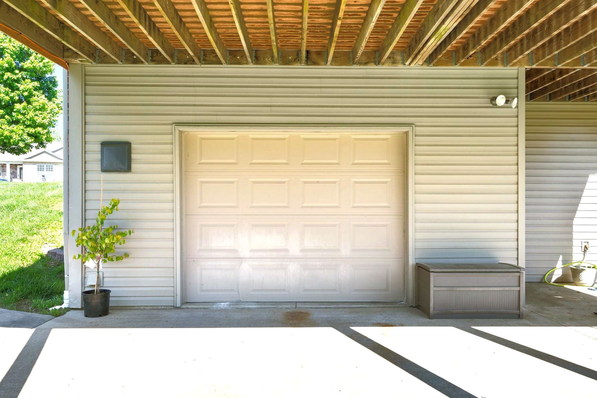 A single white garage door under a deck.