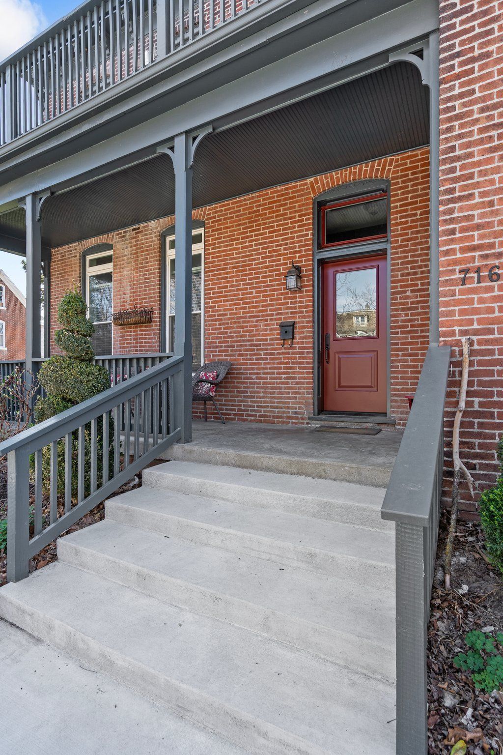 Red brick house with grey porch, stairs, and door.
