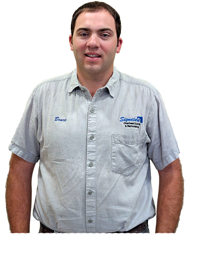 Man in a light blue uniform shirt with a logo, smiling, hands at sides.