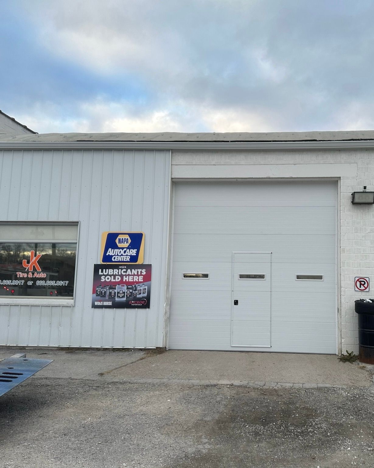 White building with garage door, sign for Napa Auto Care, and cloudy sky.
