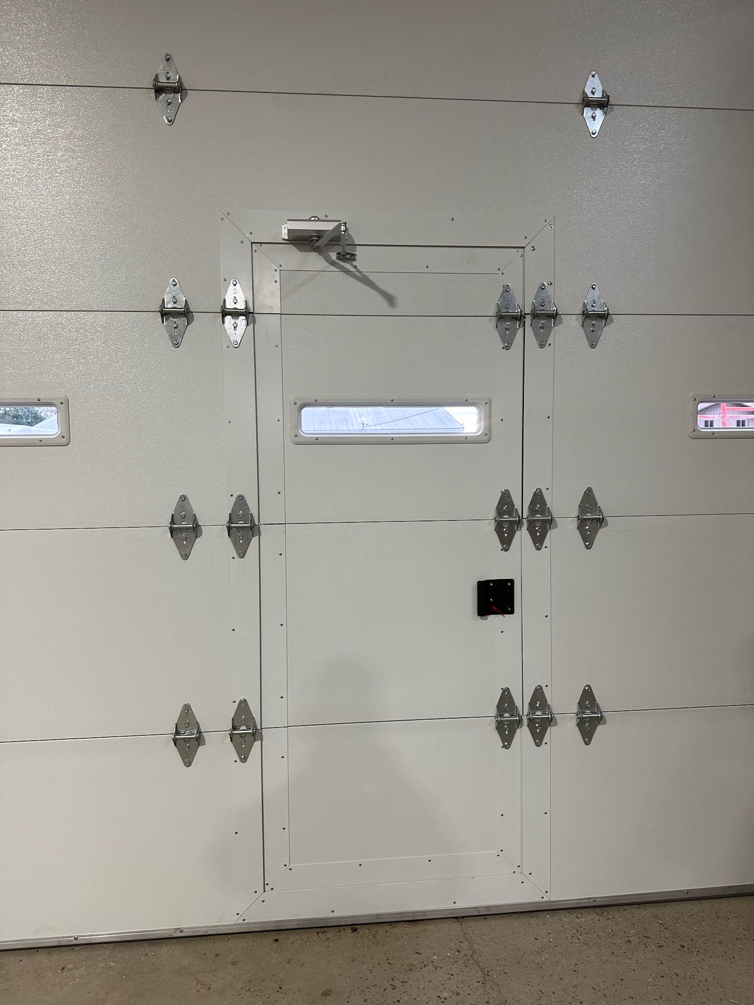 White garage door with an access door, hinges, and hardware.