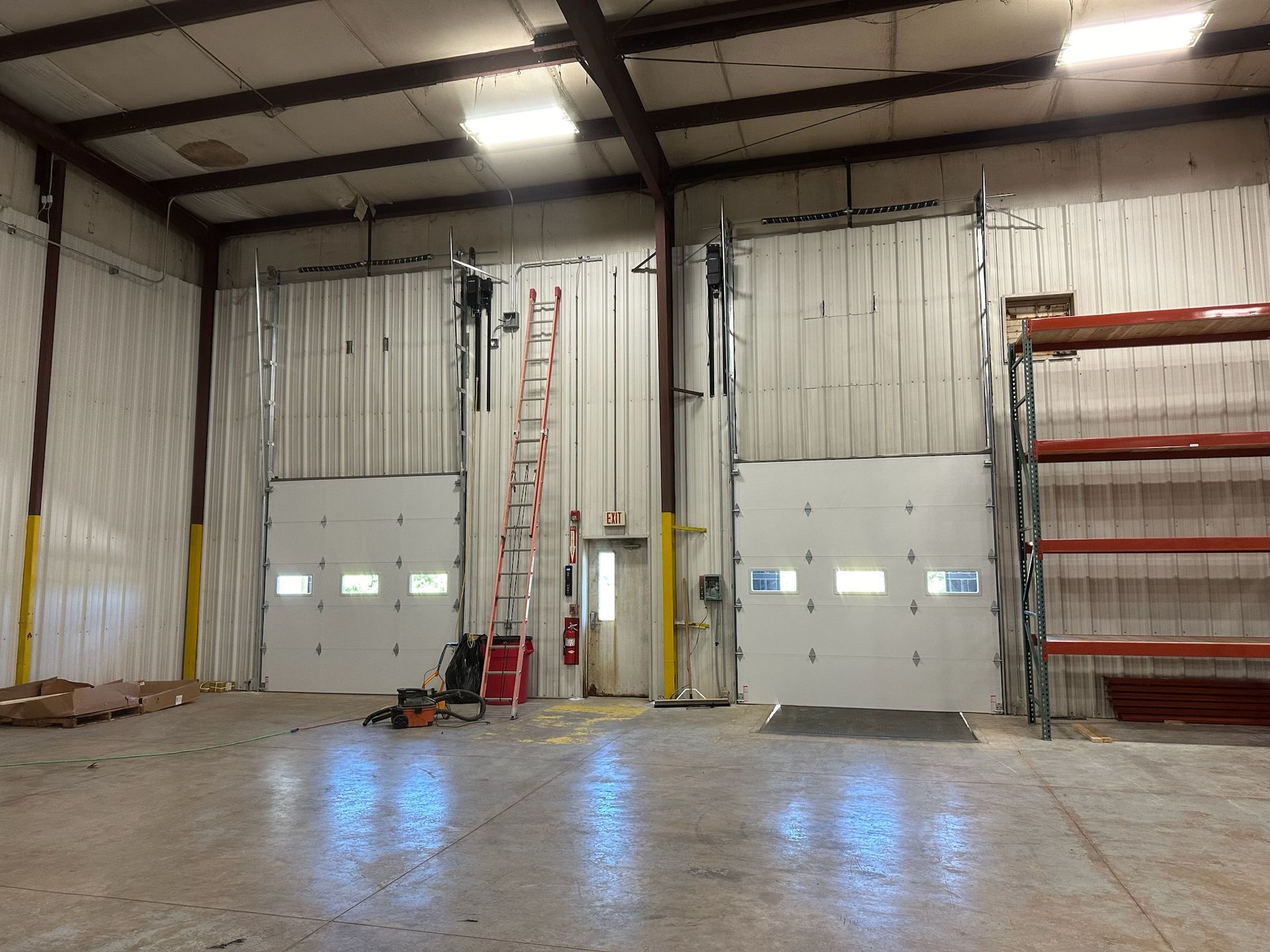 Interior warehouse with two garage doors and a ladder.