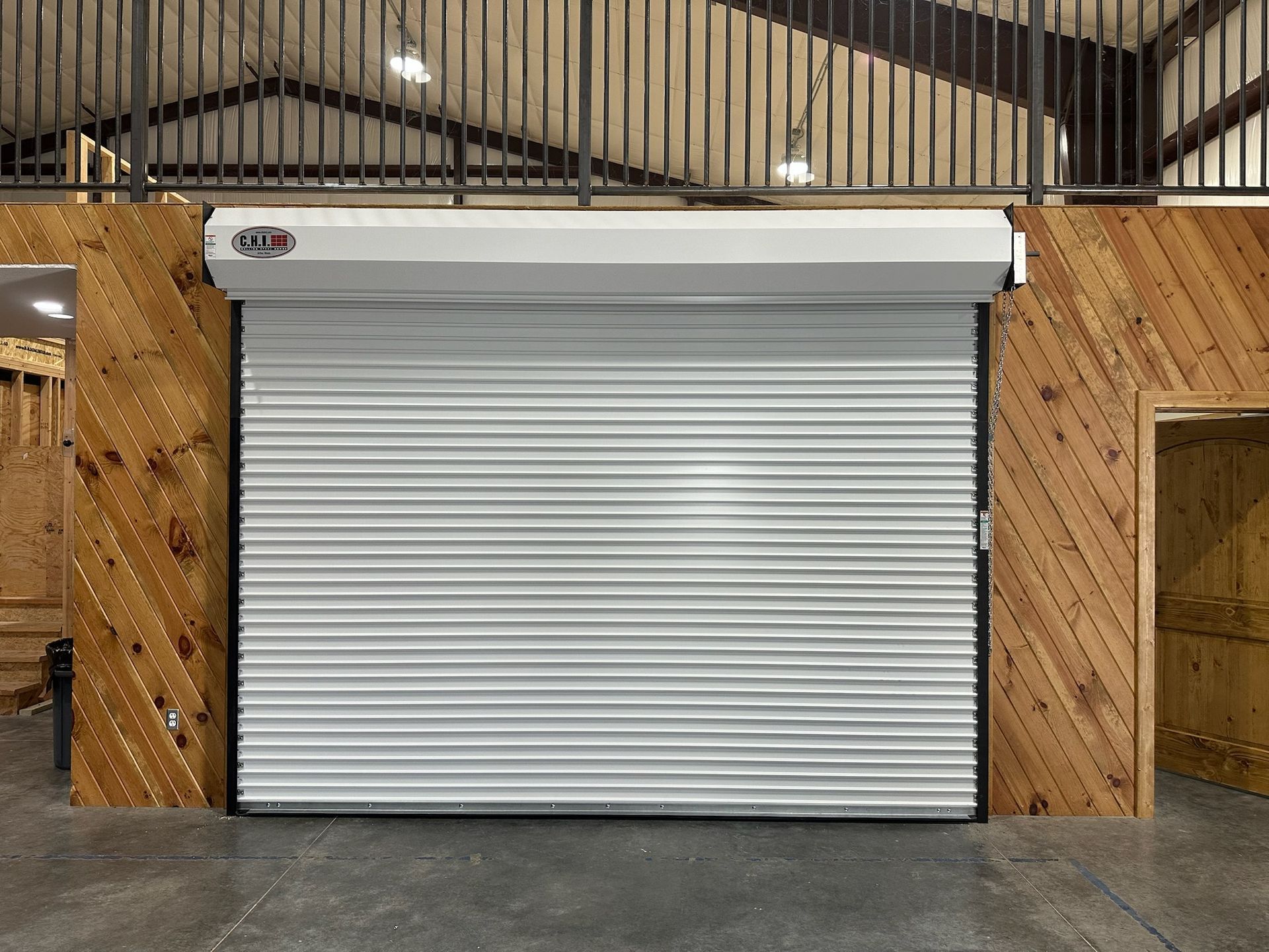 White rolling garage door with wooden paneling on either side inside a warehouse.