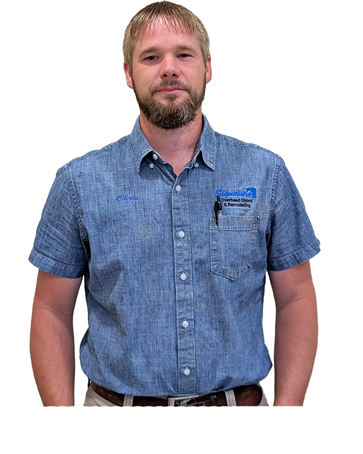 Man wearing a denim shirt, standing, with a name tag. He has a beard and is looking at the camera.