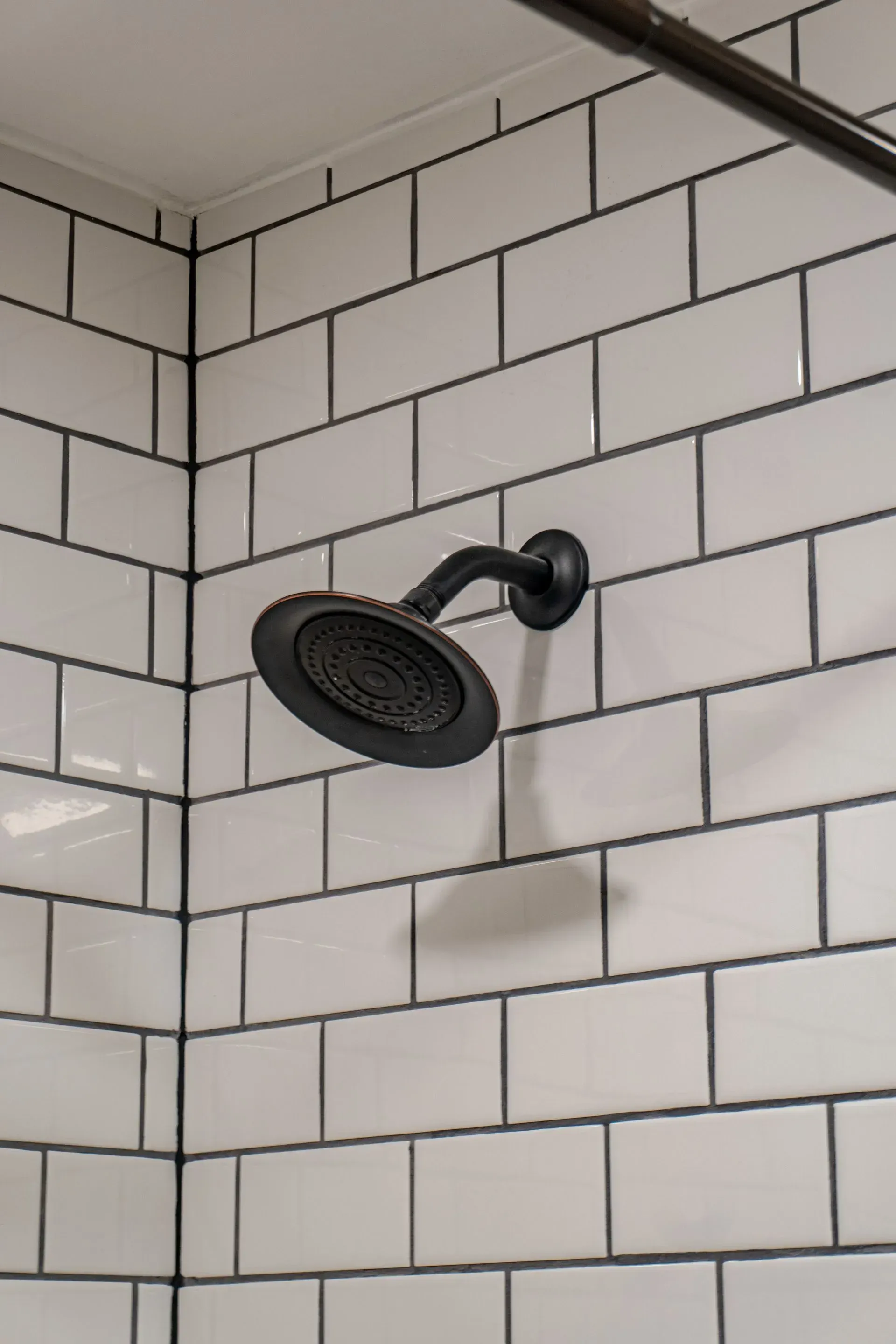 Showerhead against white subway tile with dark grout.
