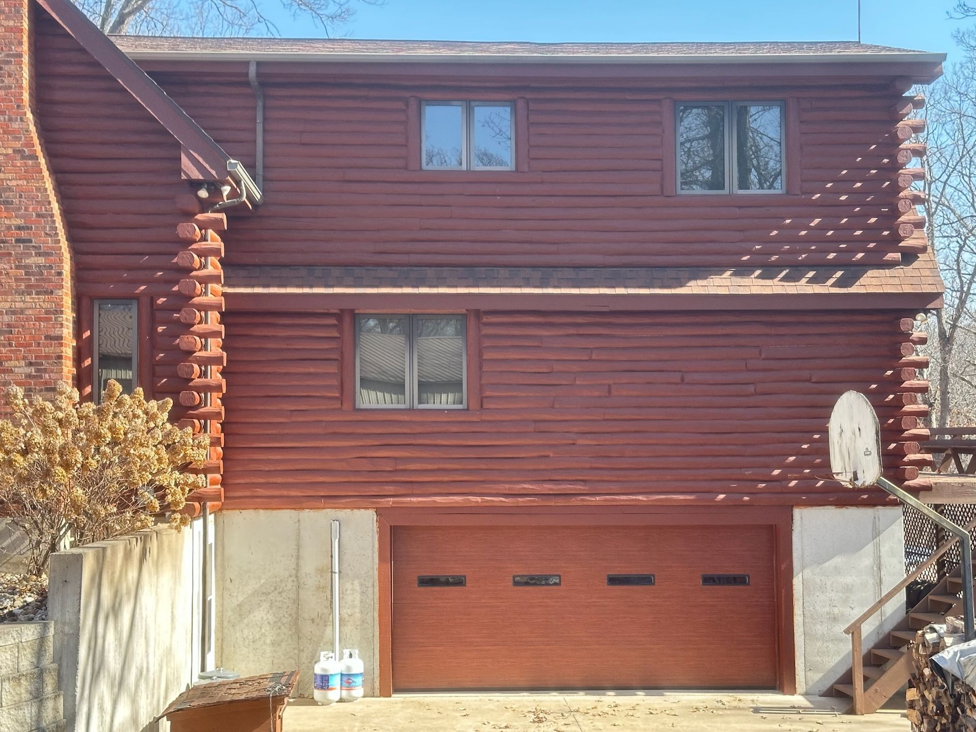 Red-painted two-story house with a garage door, windows, and a basketball hoop.