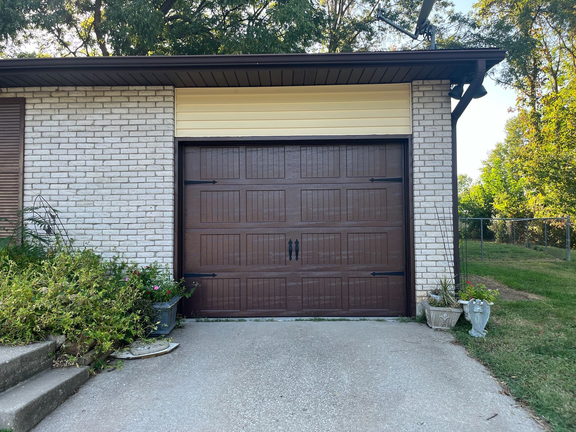 Brown garage door in a brick building with a concrete driveway.
