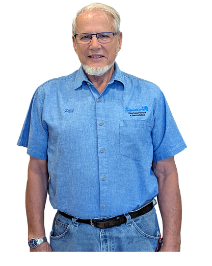 Man in blue work shirt, glasses, and jeans, smiling; stands in front of a white background.