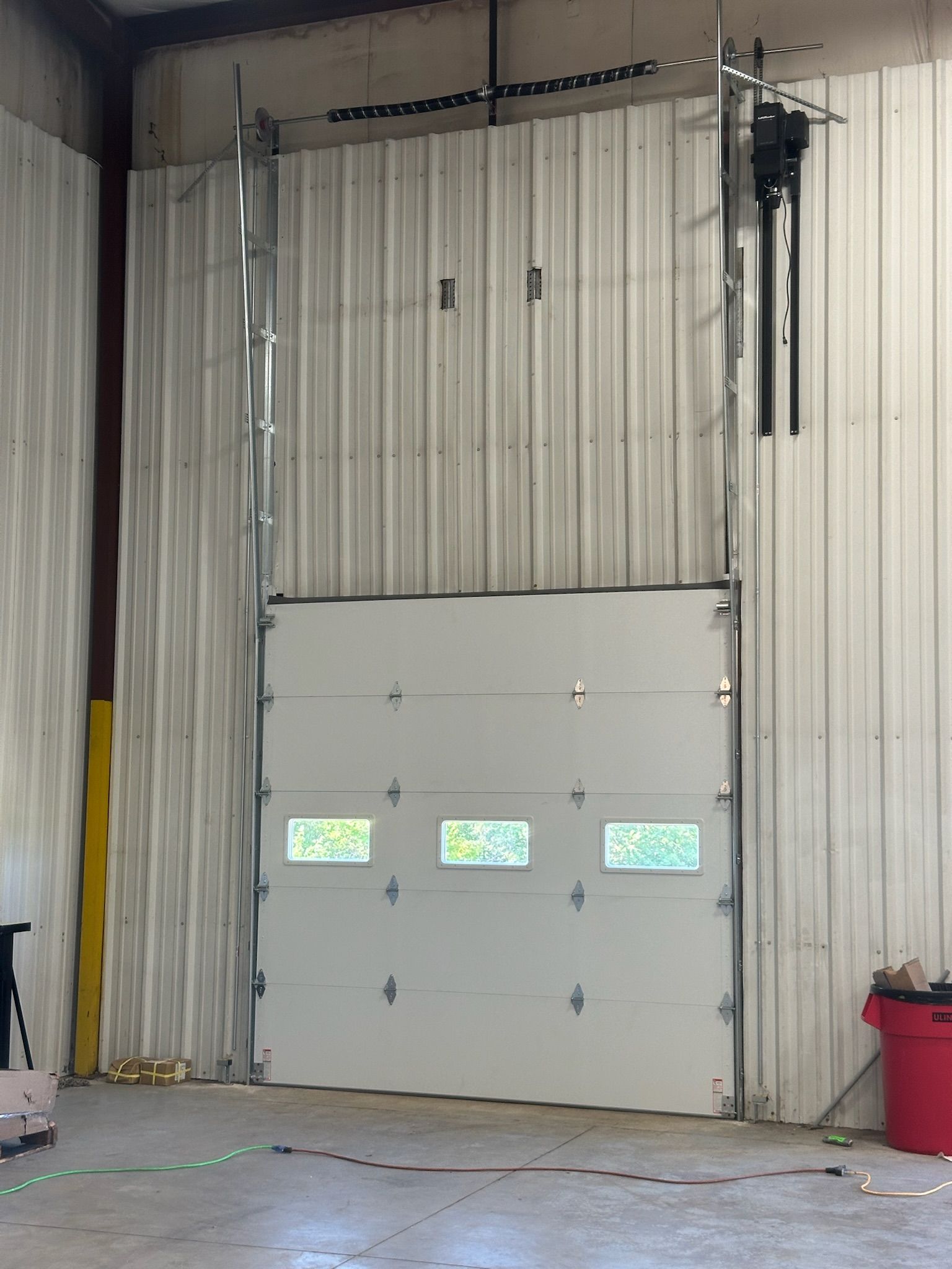Closed white garage door in a warehouse, with visible track and motor.