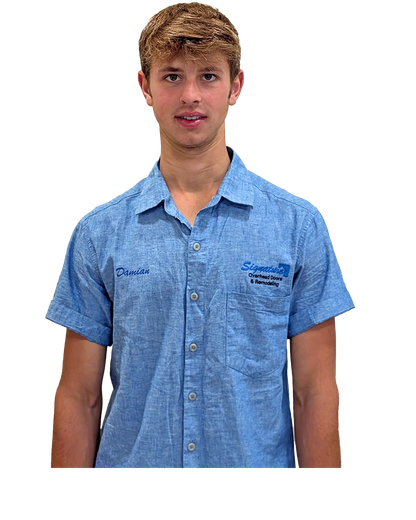 Teenager wearing a blue collared shirt smiling, standing against a white background.