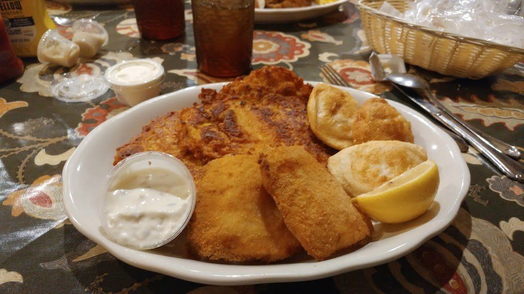 A white plate topped with fried fish and lemon slices on a table.