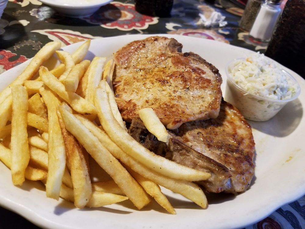 A white plate topped with pork chops and french fries.