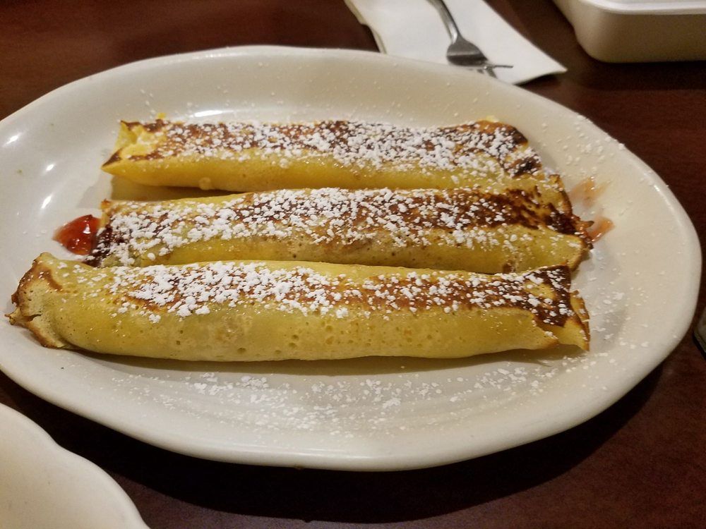 A white plate topped with three pancakes covered in powdered sugar