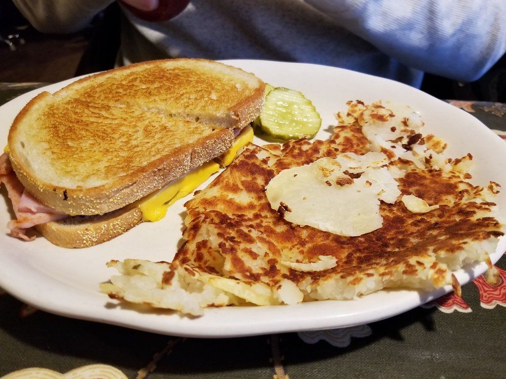A white plate topped with a grilled cheese sandwich and hash browns.