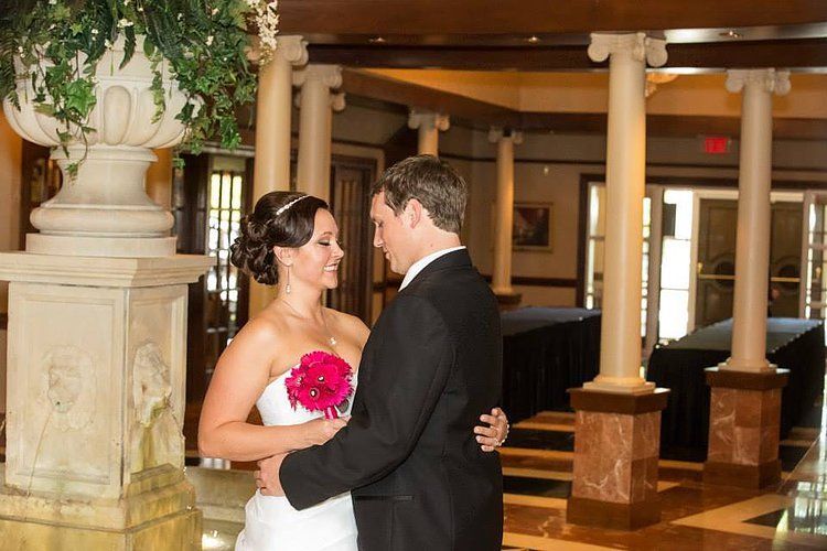 A bride and groom are posing for a picture in a room with columns.