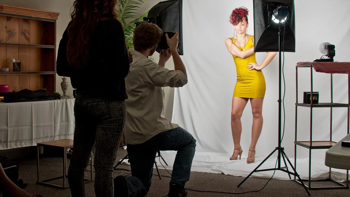 A man is taking a picture of a woman in a yellow dress.