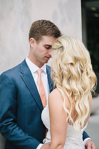 A man in a suit and tie is standing next to a woman in a wedding dress.