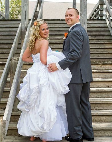 A bride and groom are posing for a picture on a set of wooden stairs.