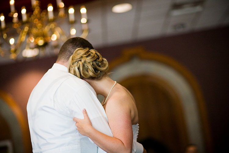 A bride and groom are hugging each other while dancing at their wedding reception.