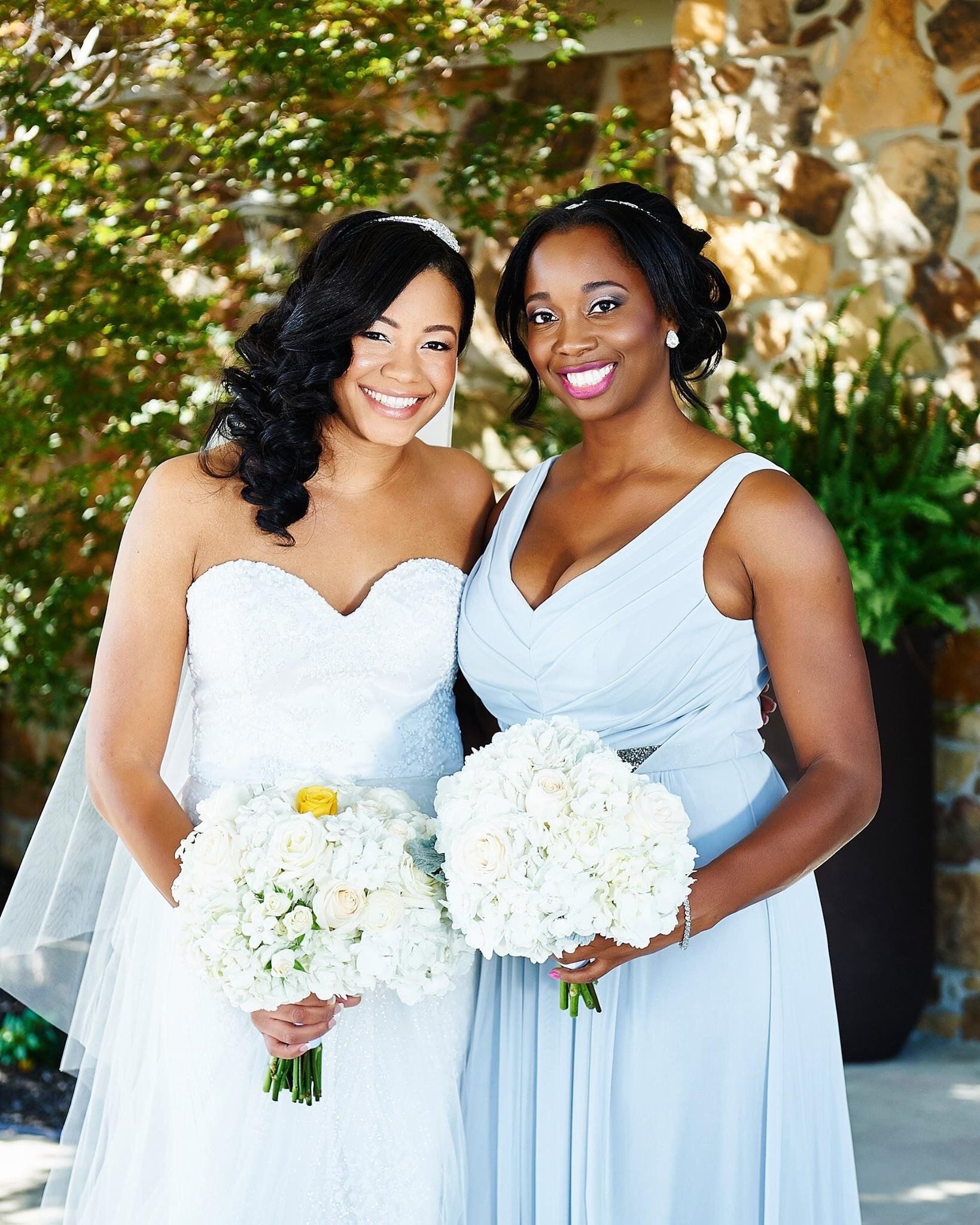A bride and her bridesmaid are posing for a picture
