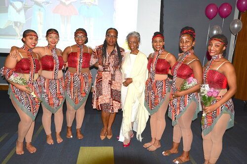 Group of dancers and two women posing, balloons in the background