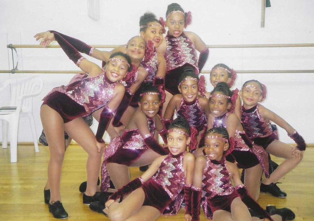 Dance team in burgundy and silver costumes posing in a dance studio.