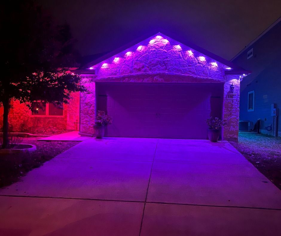Garage door and home exterior illuminated with red and purple lights at night.