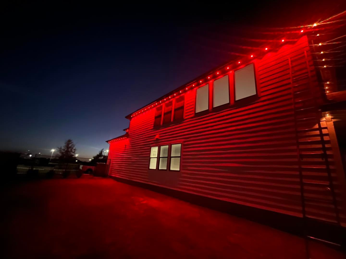 Red illuminated building at dusk with string lights.