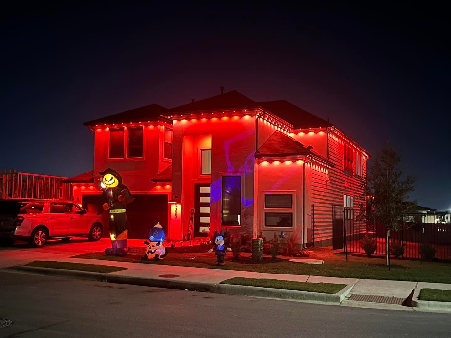 House decorated for Halloween with red lights and inflatable figures.