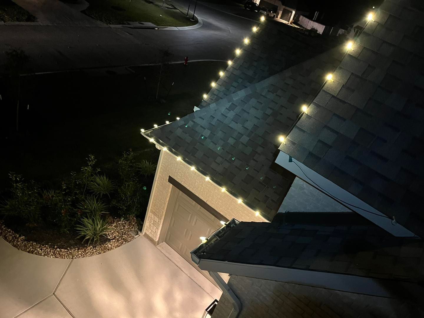 String of white lights along a house's roofline at night.
